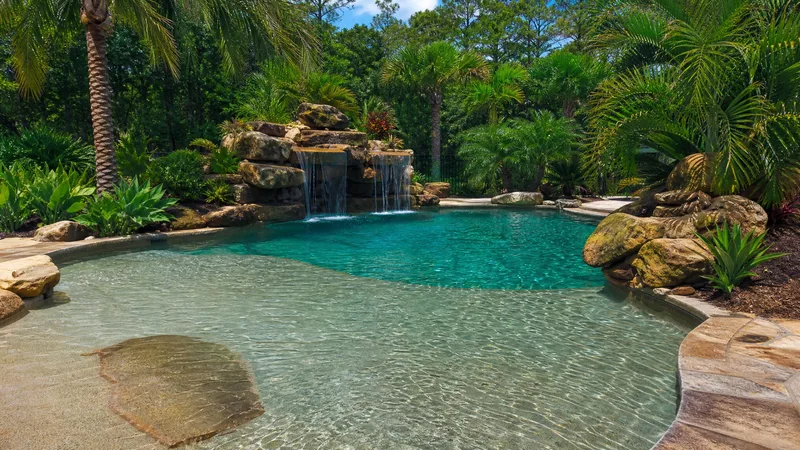 Freeform lagoon style pool with rock waterfall and tropical landscaping in Houston